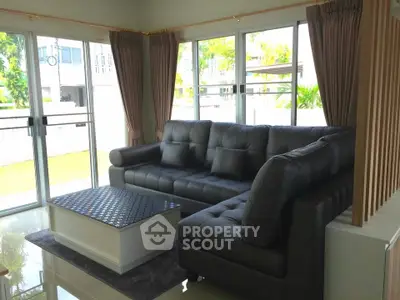 Spacious living room with modern L-shaped sofa and large windows offering natural light.