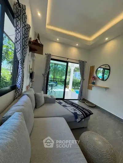 Stylish living room with large windows and garden view, featuring modern decor and cozy seating.