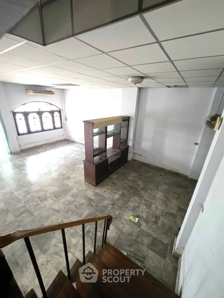 Spacious living room with tiled flooring and large window, ideal for customization.