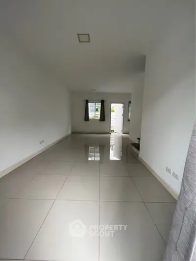 Spacious and bright unfurnished living room with large windows, glossy tiled flooring, and neutral color palette ready for personalization.