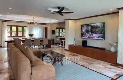 Spacious living room with elegant dining area and large TV, featuring modern decor and ample natural light.