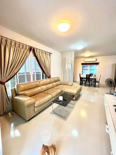 Spacious living room with elegant leather sofa and dining area, perfect for modern living.