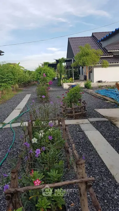 Charming garden pathway leading to a modern house with lush greenery and vibrant flowers.