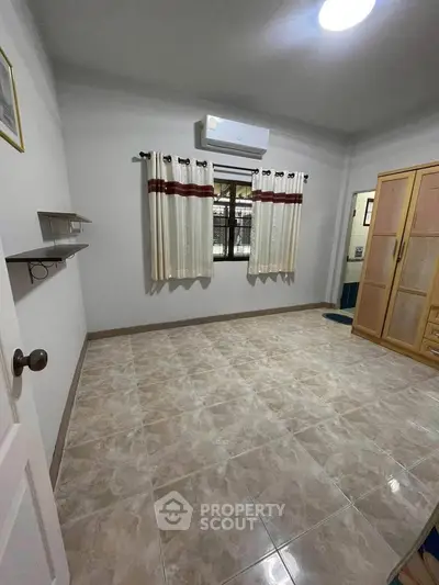 Spacious unfurnished bedroom with tiled flooring and air conditioning, ready for customization.