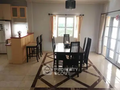 Spacious dining area with elegant marble flooring and natural light, adjacent to a modern kitchen.