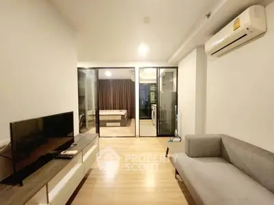 Modern living room with sleek design, featuring a cozy sofa, TV unit, and glass partition leading to a bedroom.