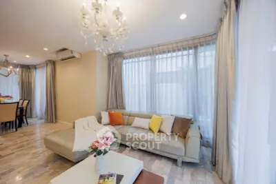 Elegant living room with chandelier, cozy sofa, and dining area in modern home.