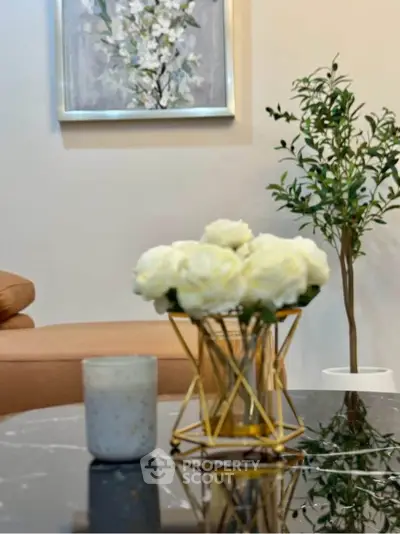 Elegant living room with modern decor and stylish furniture, featuring a marble coffee table and floral accents.