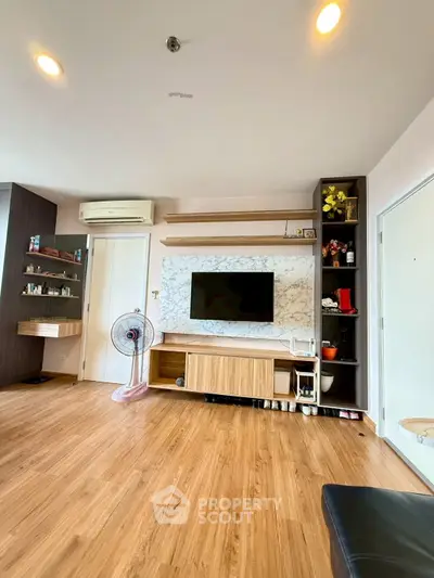 Modern living room with wooden flooring, wall-mounted TV, and stylish shelving.