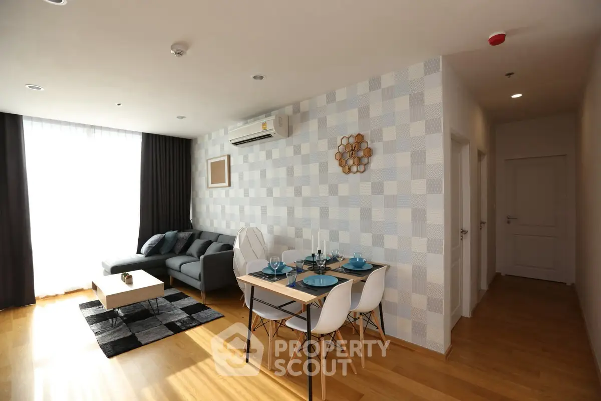 Modern living room with stylish decor and dining area, featuring wooden flooring and ample natural light.