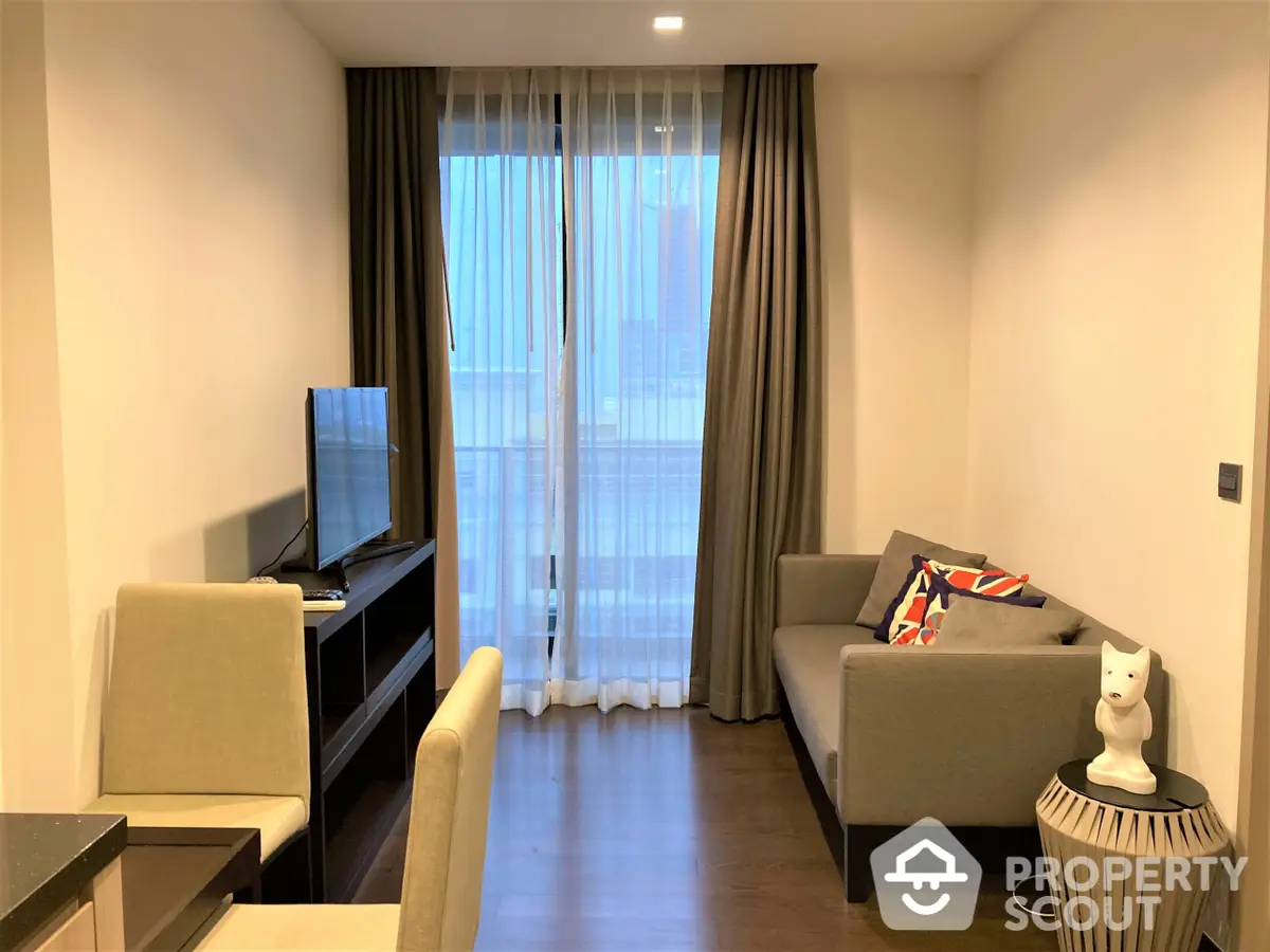 Modern living room with sleek furniture and natural light streaming through floor-to-ceiling windows, complemented by warm wooden flooring.