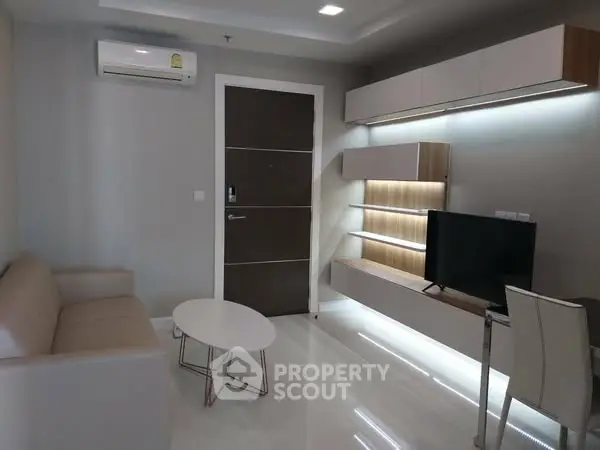 Modern living room with sleek furniture and wall-mounted TV in a stylish apartment.