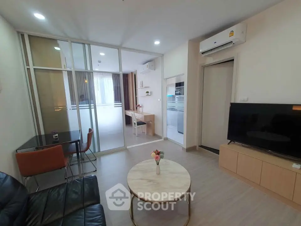 Modern living room with glass partition, sleek furniture, and air conditioning.