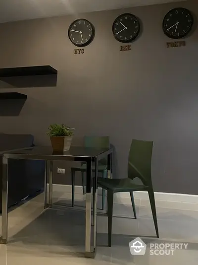 Modern dining area with sleek table and chairs, featuring world clocks on the wall.