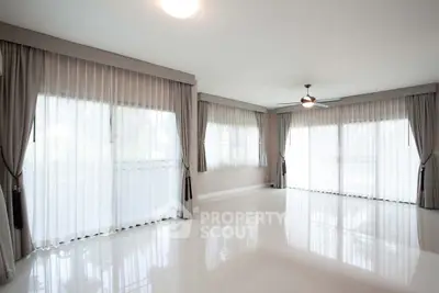 Spacious empty living room with large windows and elegant curtains
