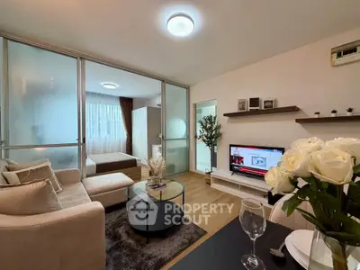 Modern living room with open layout and stylish decor, featuring a cozy seating area and a view into the bedroom.