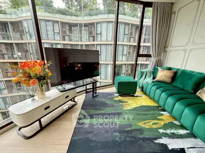Luxurious living room with green velvet sofa and large TV, modern decor and floor-to-ceiling windows.