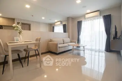 Modern living room with elegant decor and natural light, featuring a cozy sofa and dining area.