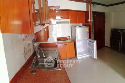 Spacious kitchen with wooden cabinets and modern appliances in a cozy apartment.
