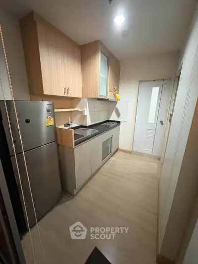 Modern compact kitchen with sleek wooden cabinets and stainless steel appliances