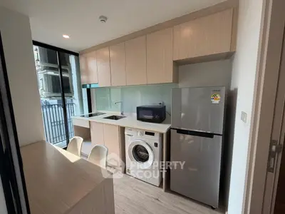 Modern kitchen with sleek cabinetry, washing machine, and fridge in a compact apartment.