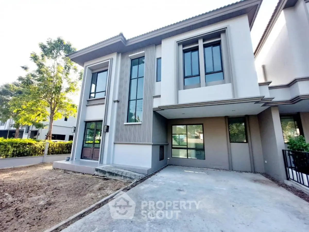 Modern two-story house with large windows and driveway in a serene neighborhood.