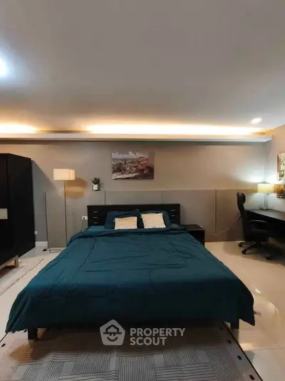 Spacious bedroom with modern decor and cozy lighting, featuring a comfortable bed and stylish furnishings.