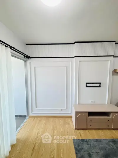 Modern living room with elegant paneling and light wood flooring, featuring a sleek TV stand.