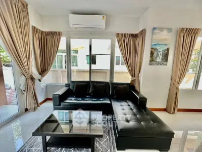 Modern living room with black leather sofa and large windows