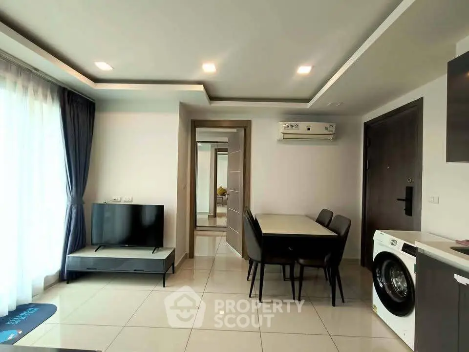 Modern living room with dining area and washing machine, featuring sleek furniture and bright lighting.