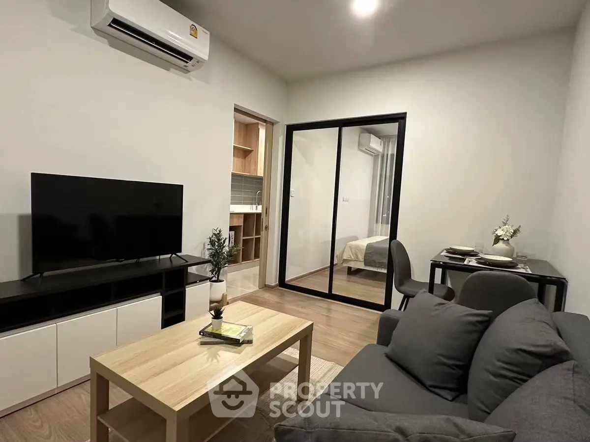 Modern living room with sleek furniture and open view into a cozy bedroom.