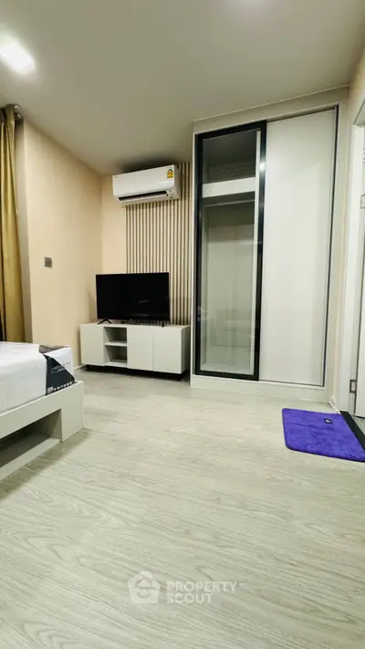 Modern bedroom with sleek design, featuring a wall-mounted TV, air conditioning, and a spacious wardrobe.