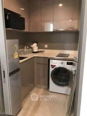 Compact modern kitchen with appliances including fridge and washing machine.