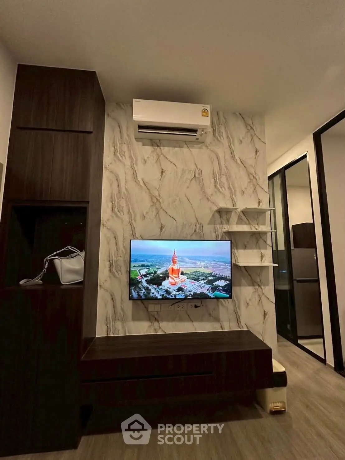 Modern living room with wall-mounted TV and air conditioning, featuring stylish marble accent wall.