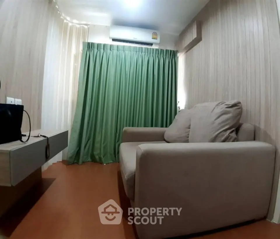 Cozy small living room with beige armchair and green curtains, perfect for relaxation.