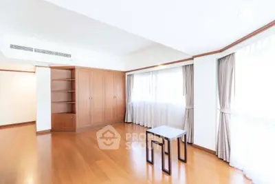 Spacious and bright living room with wooden flooring and large windows.