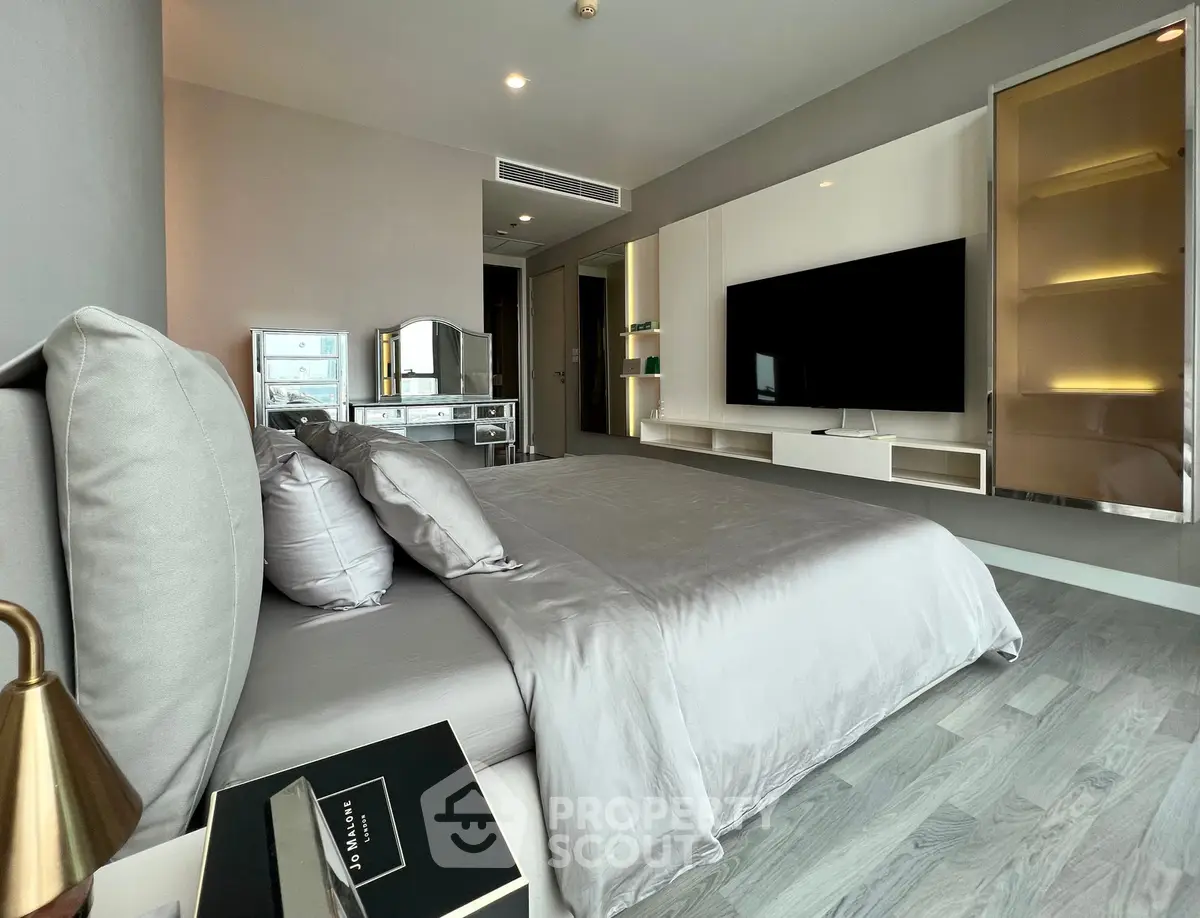 Luxurious modern bedroom with sleek design and large TV, perfect for relaxation and comfort.