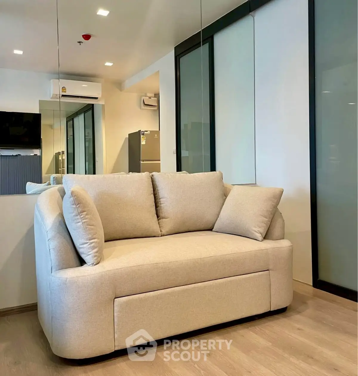 Modern living room with stylish beige sofa and mirrored wall accents.