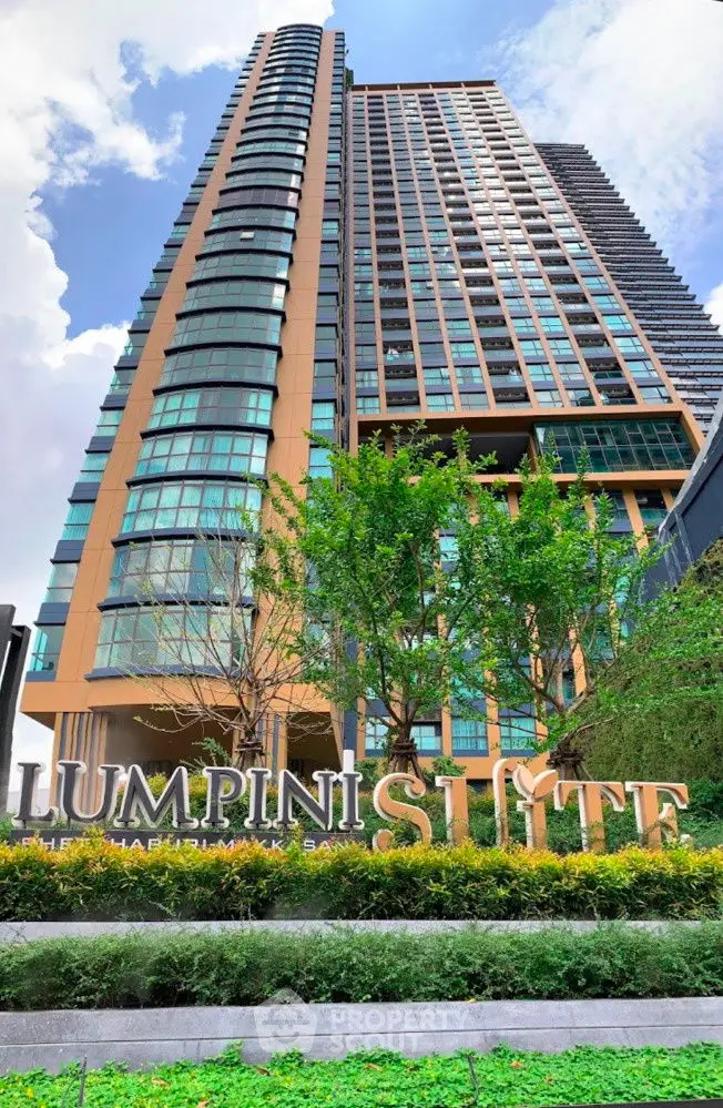 Stunning modern high-rise building with lush greenery and clear blue sky.