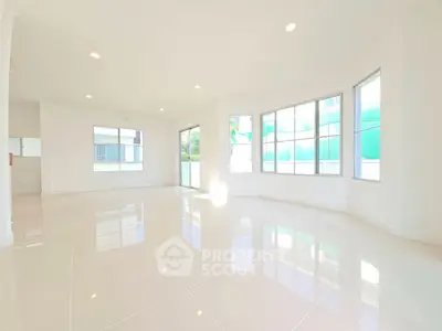 Spacious sunlit living room with large windows and glossy tiled floors