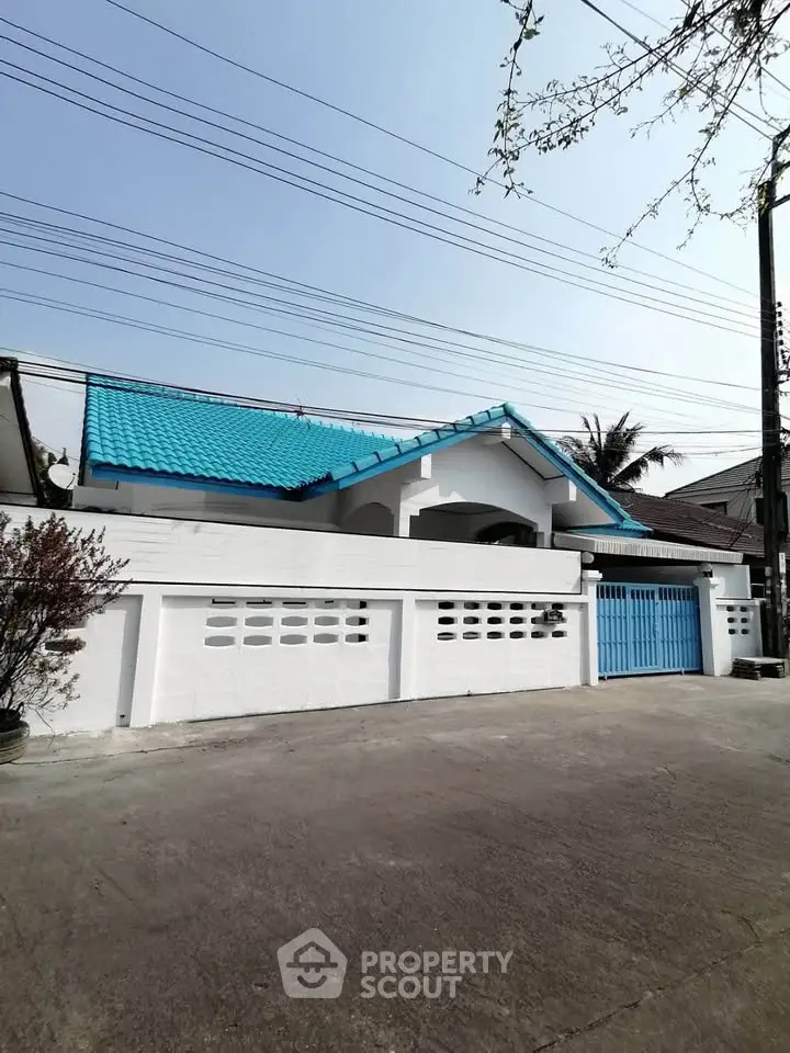 Charming white house with blue roof and gated entrance in a serene neighborhood.
