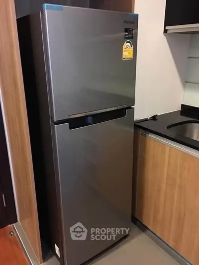 Modern kitchen with sleek stainless steel refrigerator and wooden cabinetry.