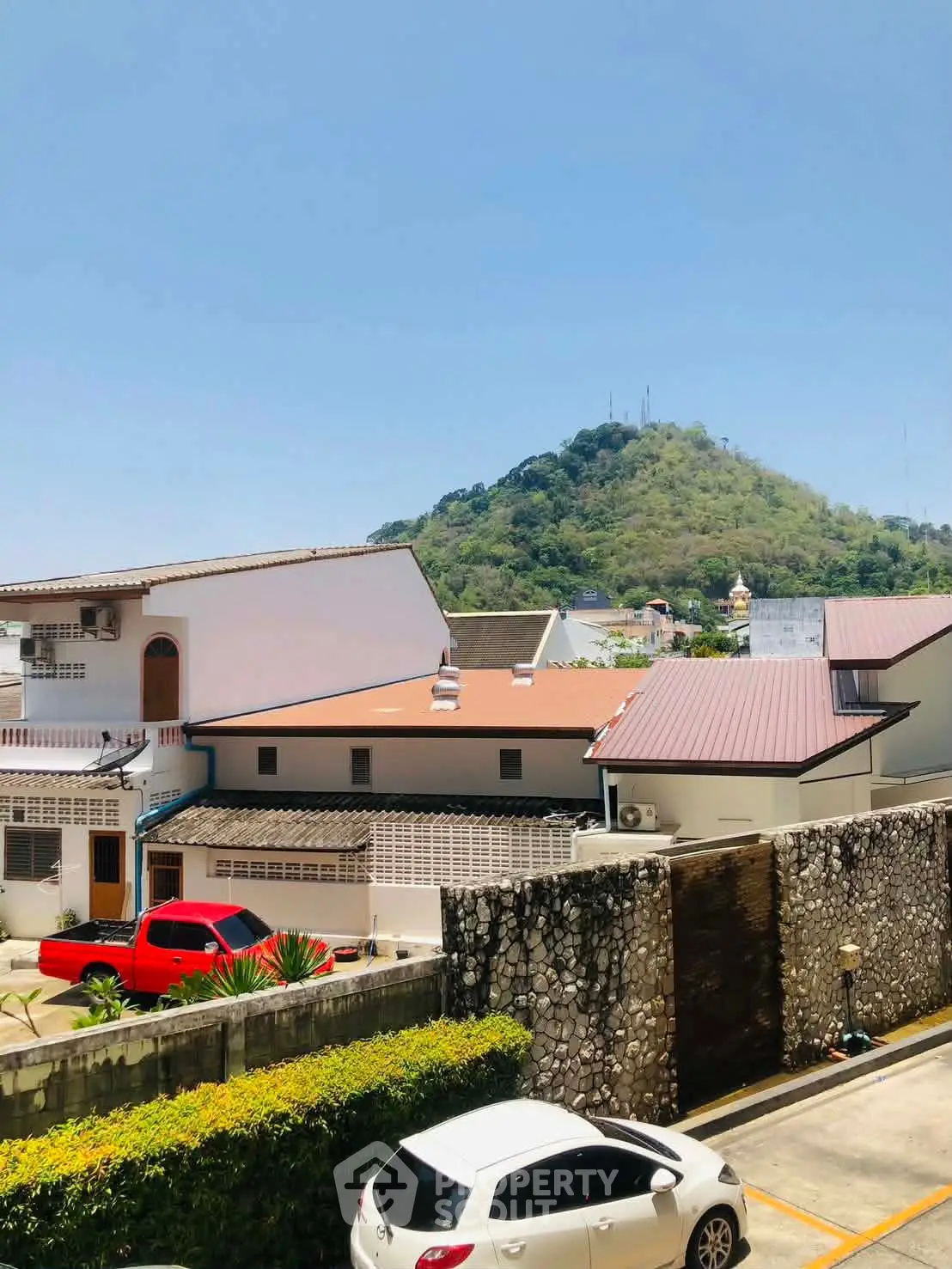 Scenic view of residential area with mountain backdrop and parked cars.