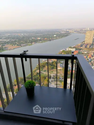 Stunning river view from high-rise balcony with sleek railing and small table.