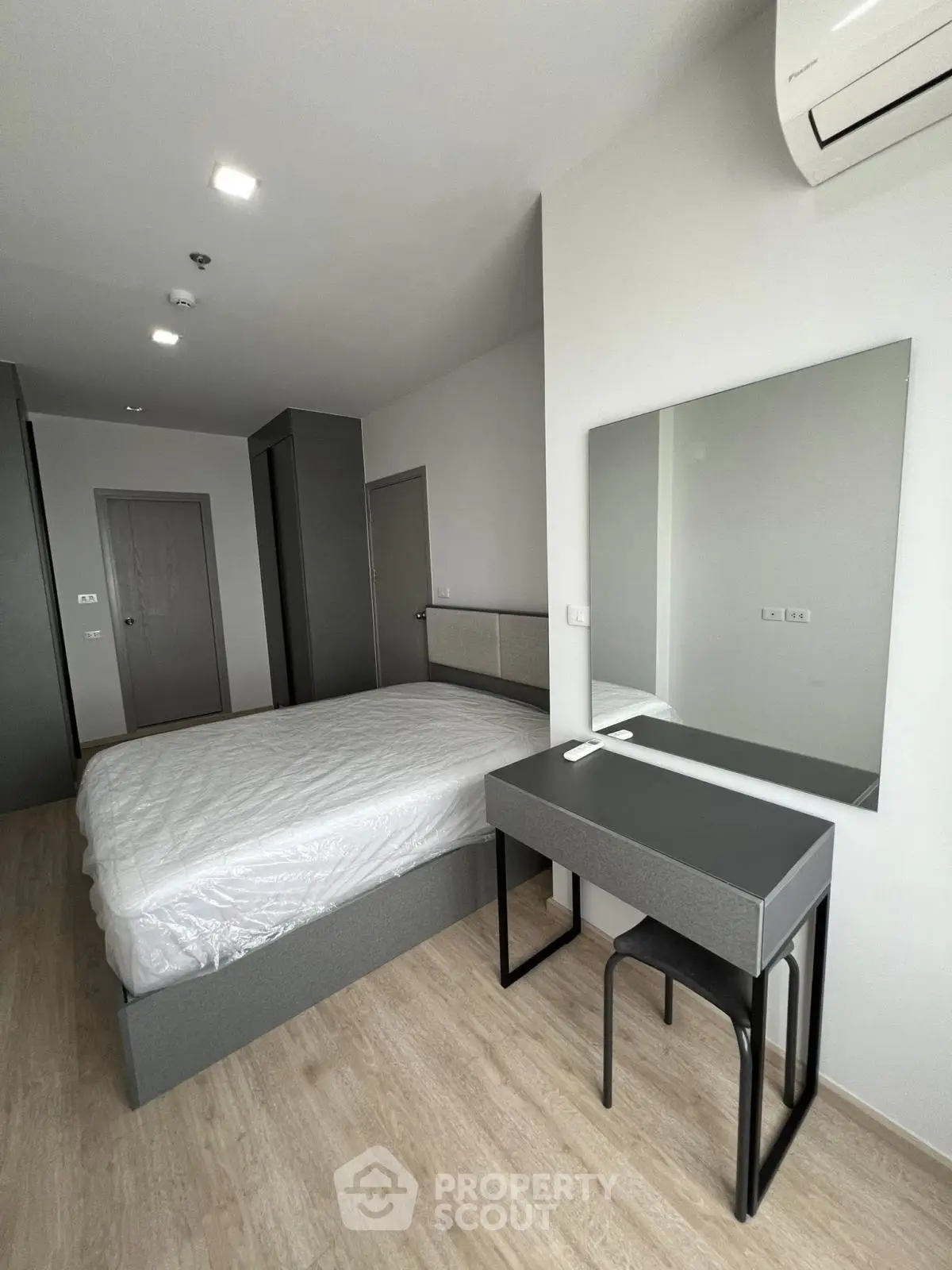 Modern bedroom with sleek furniture and air conditioning in a contemporary apartment.