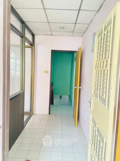 Simple hallway with tiled floor leading to a small room