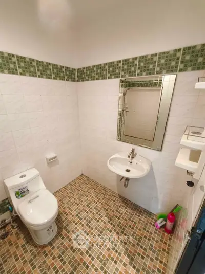 Modern bathroom with tiled walls and floor, featuring a toilet and sink.