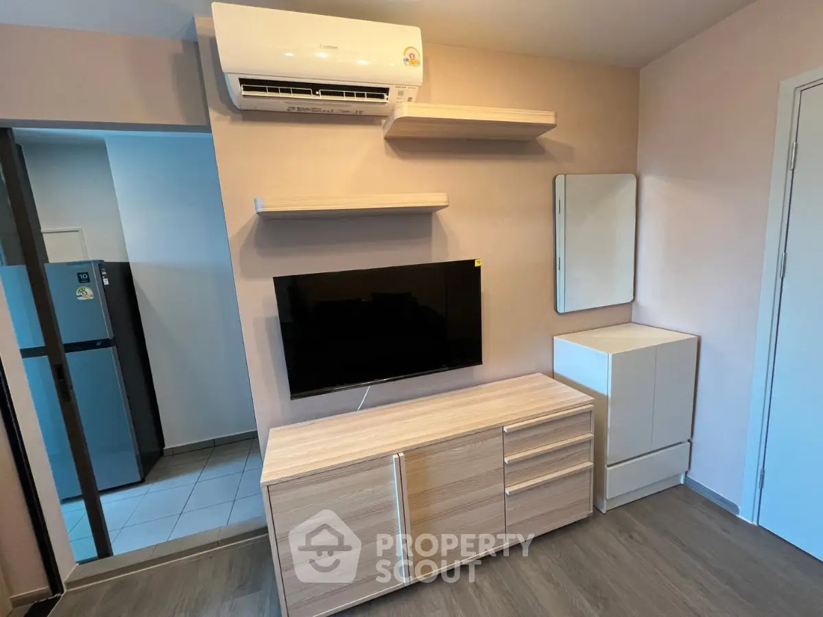 Modern living room with sleek wooden furniture and mounted TV, featuring air conditioning and minimalist decor.