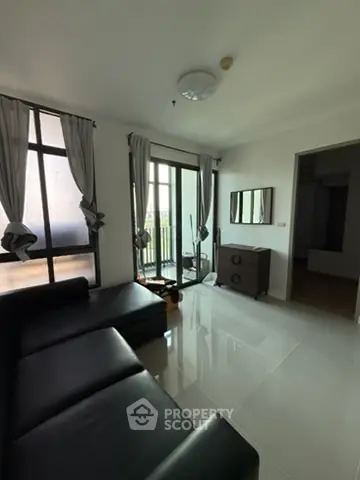 Modern living room with sleek black sofa and large windows offering natural light