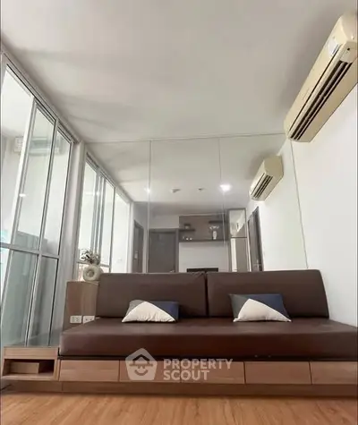 Modern living room with sleek brown sofa and mirrored wall design